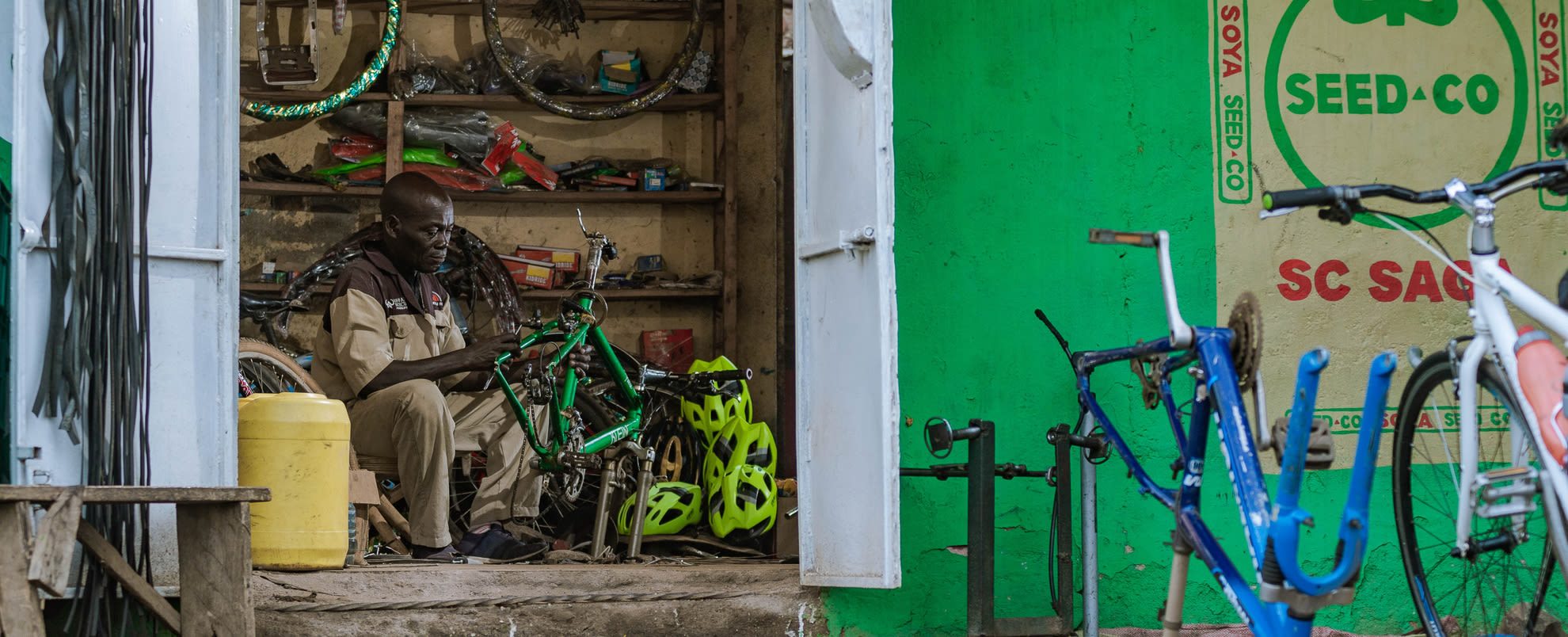 An image of an African man fixing a bike in a repair shop. 